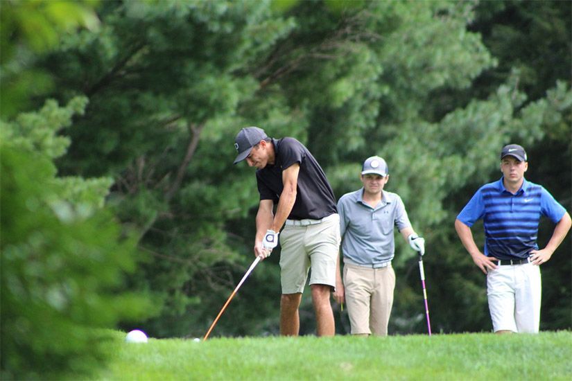 A group of men are playing golf on a golf course.