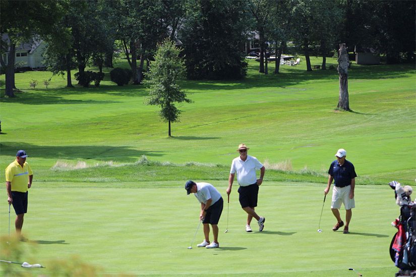 A group of men are playing golf on a golf course.