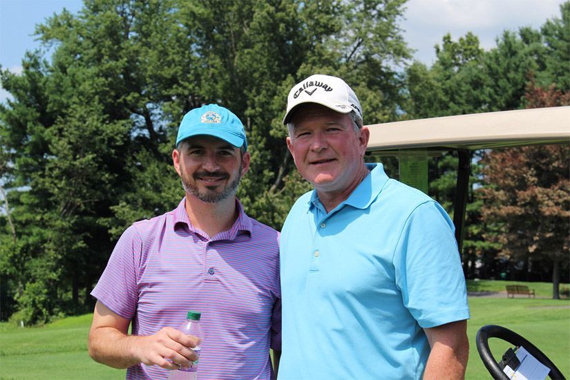 Two men are standing next to each other on a golf course.