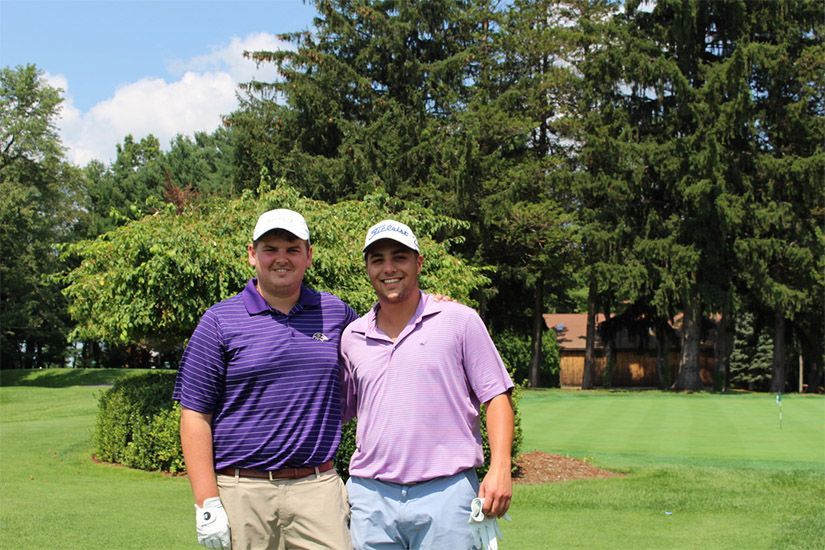 Two men are posing for a picture on a golf course.