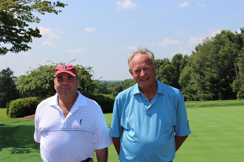 Two men are standing next to each other on a golf course.