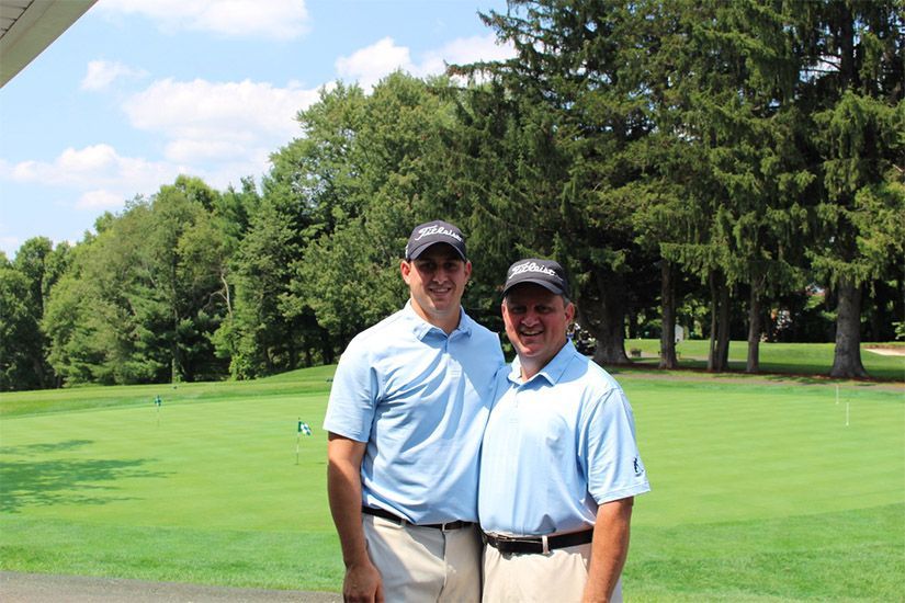 Two men are posing for a picture on a golf course