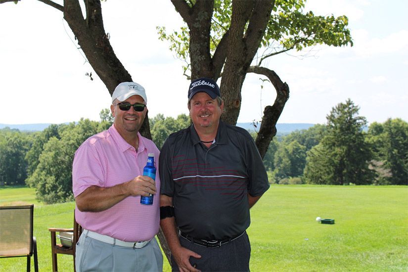 Two men are standing next to each other on a golf course.