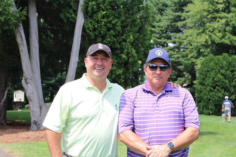 Two men are posing for a picture on a golf course.