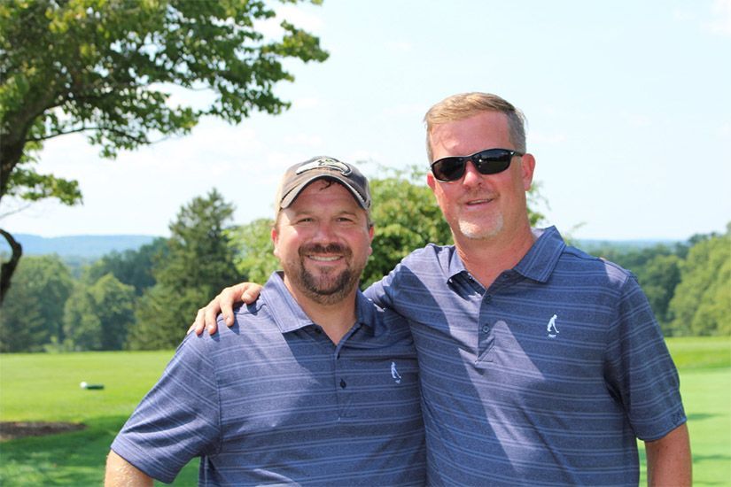 Two men are posing for a picture on a golf course.