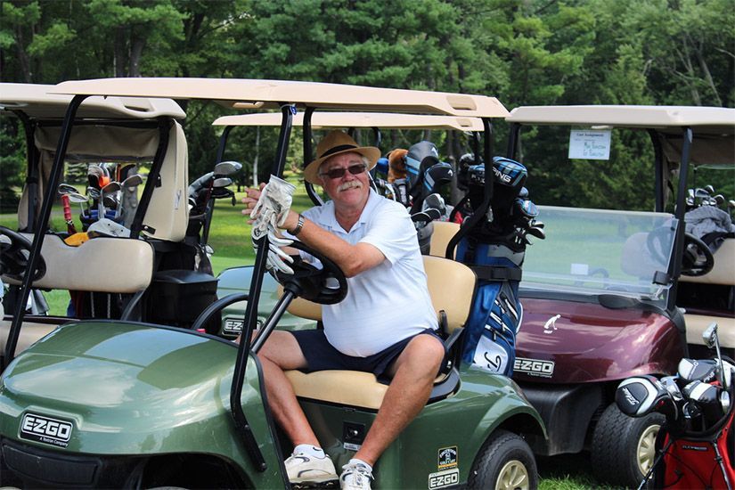 A man is sitting in a golf cart on a golf course.