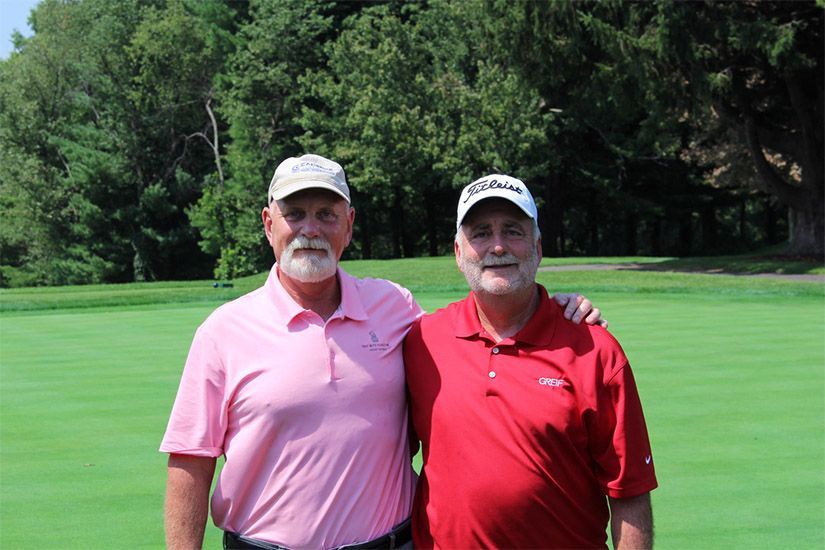 Two men are posing for a picture on a golf course.