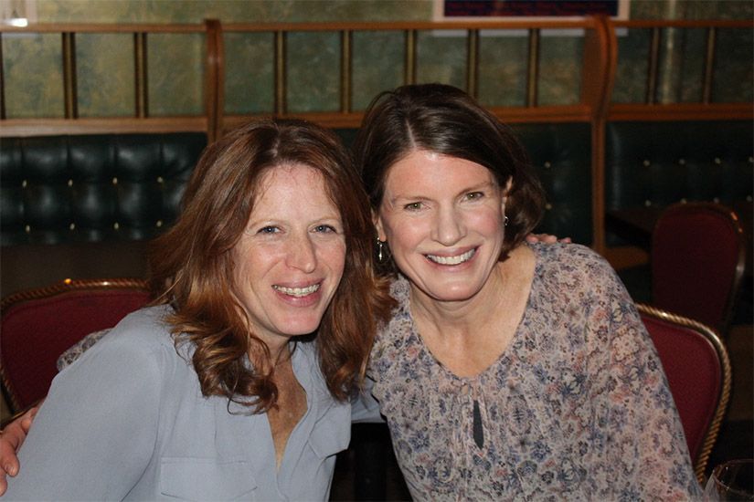 Two women are posing for a picture together in a restaurant.