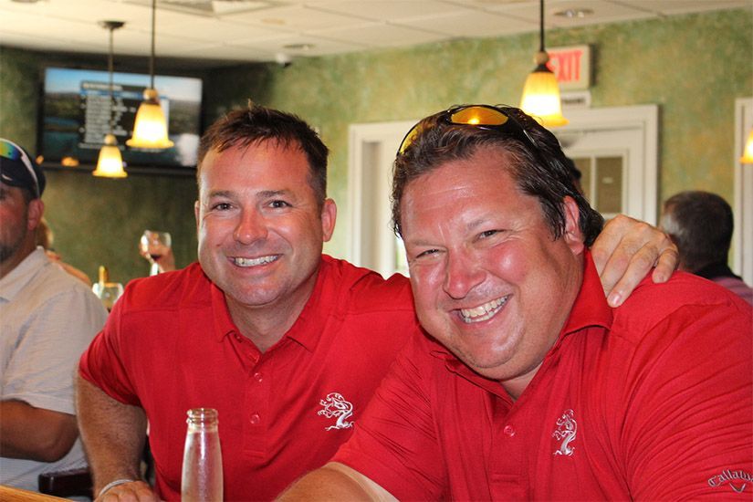 Two men in red shirts are posing for a picture in a restaurant.