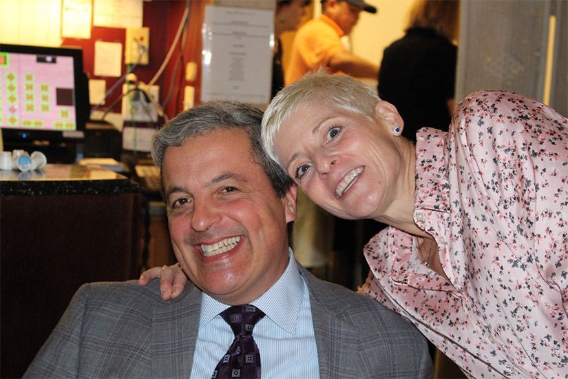 A man and a woman are posing for a picture and smiling for the camera.