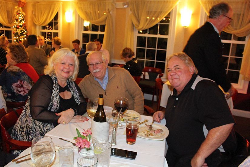 A group of people are sitting at a table with a bottle of wine
