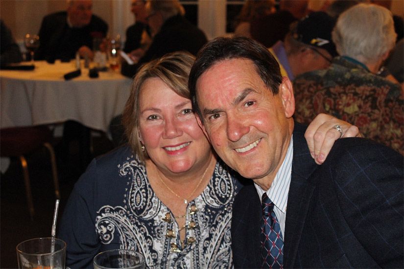 A man and a woman are posing for a picture while sitting at a table.
