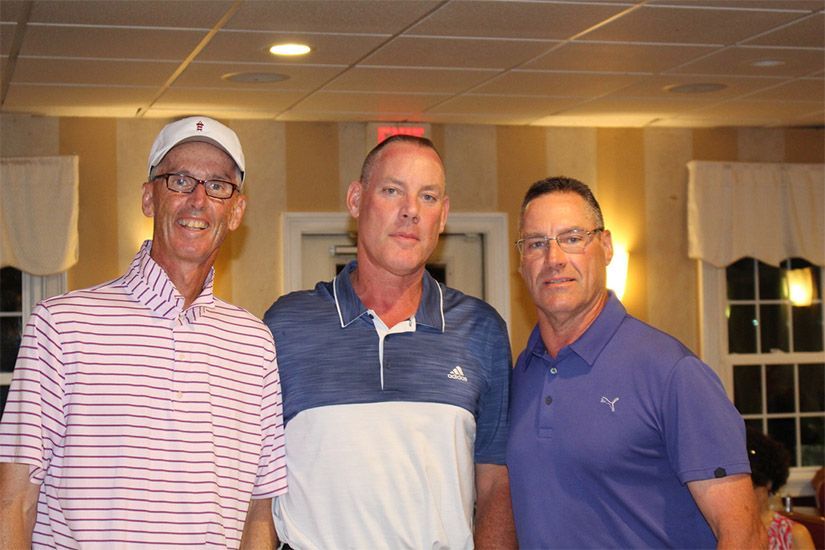 Three men are posing for a picture together in a room.