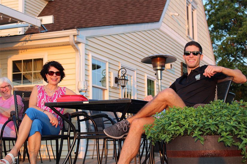 A man and a woman are sitting at a table in front of a house.