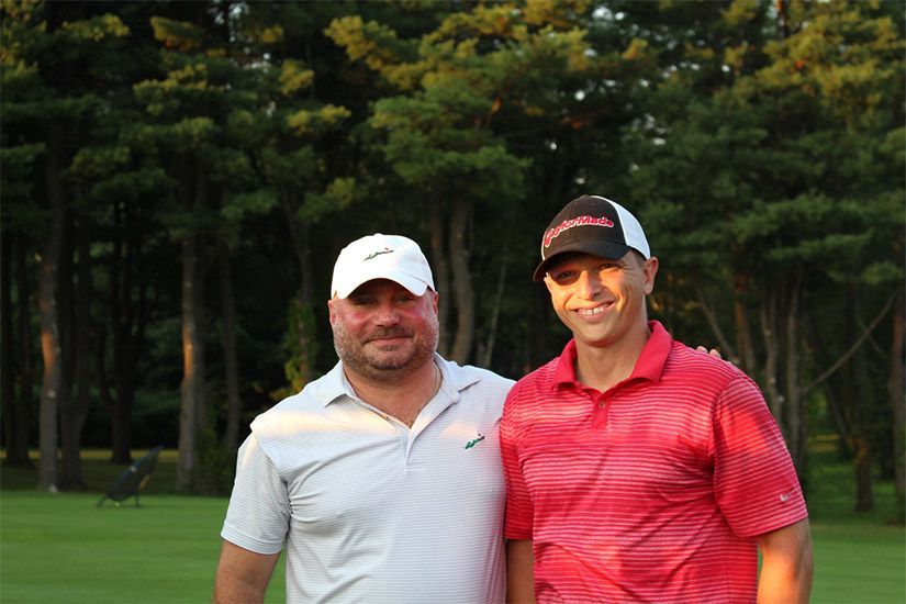 Two men are posing for a picture on a golf course.