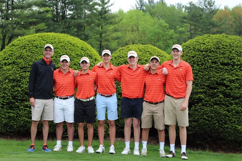 A group of young men are posing for a picture on a golf course.
