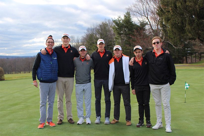 A group of young men are posing for a picture on a golf course.