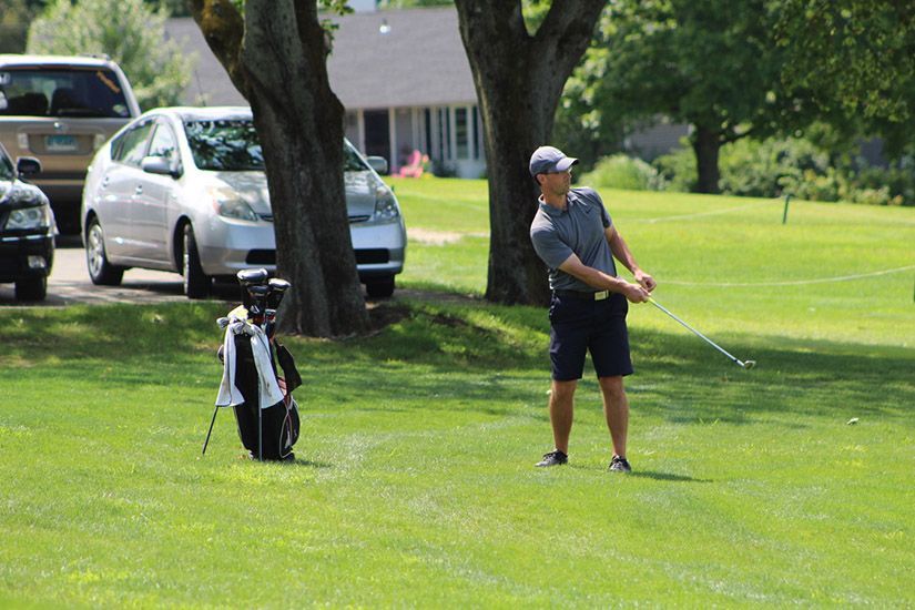 A man is swinging a golf club on a golf course.
