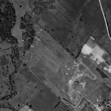 An aerial view of a field with a house in the middle of it.