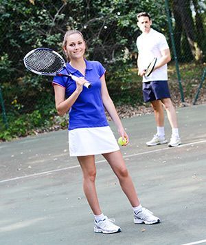 A woman in a blue shirt is holding a tennis racquet