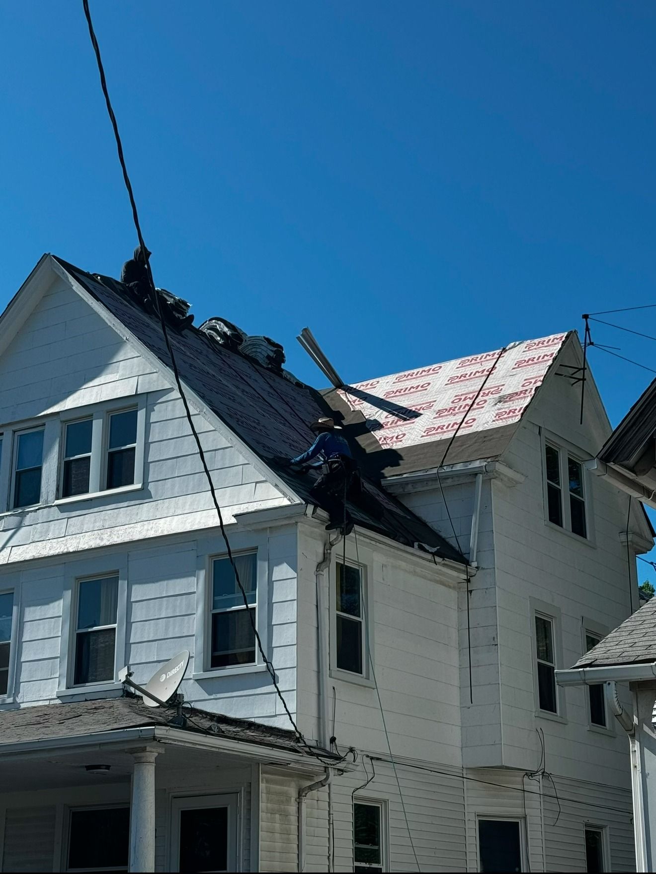 A man is working on the roof of a white house