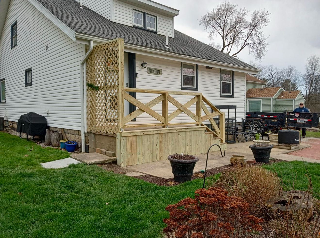 A white house with a wooden deck in front of it.