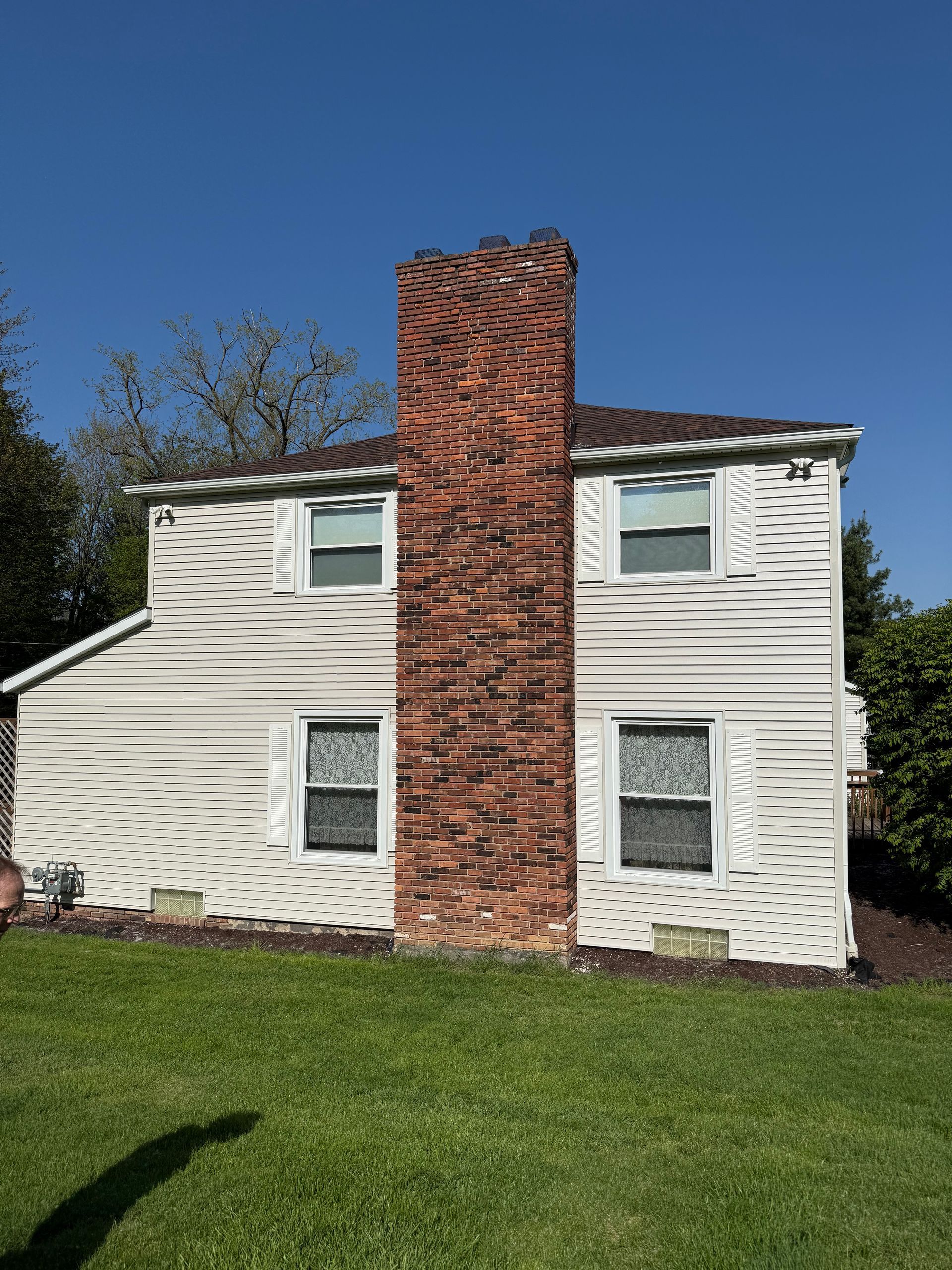 A white house with a brick chimney on the side