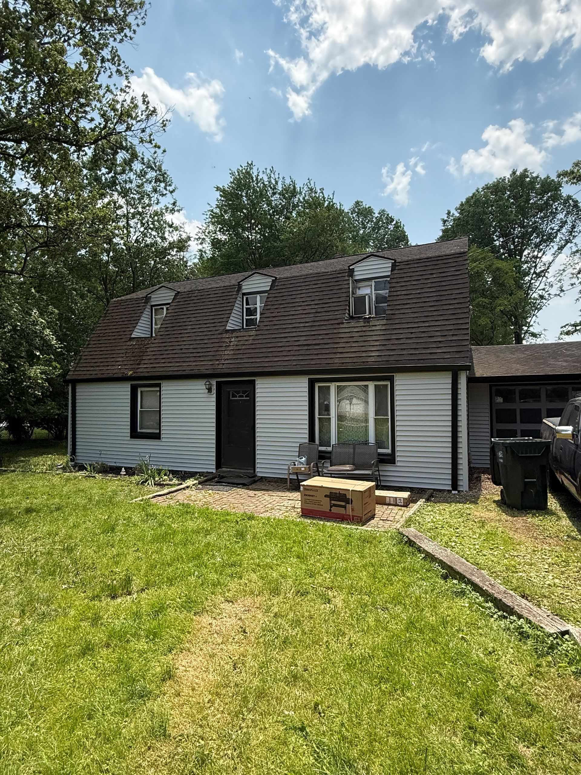 A white house with a brown roof is sitting in the middle of a lush green field.