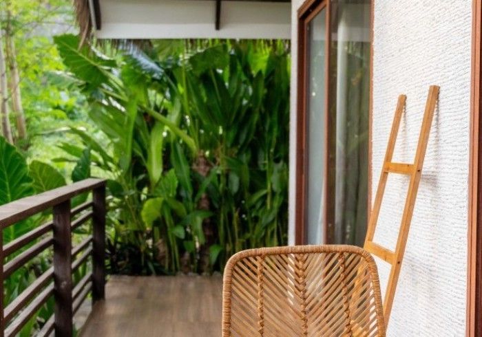 A wicker chair is sitting on a balcony next to a ladder.