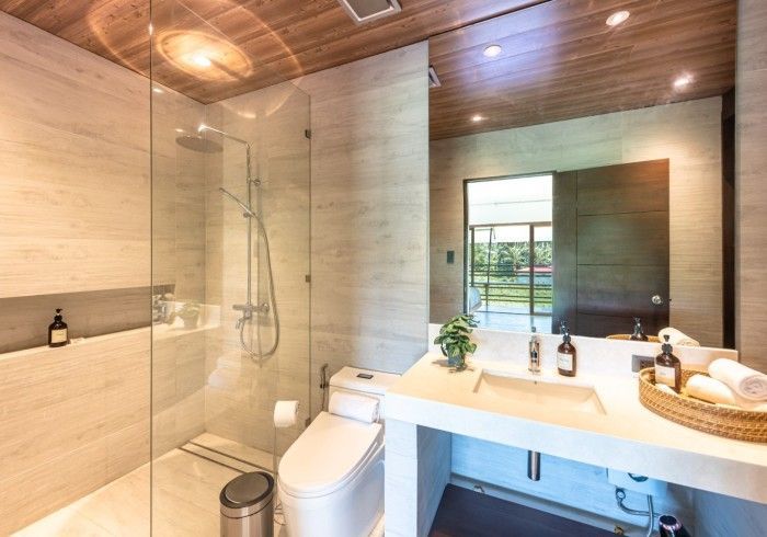 A bathroom with a toilet , sink , shower and mirror.