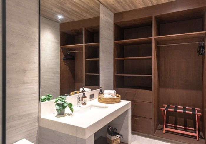 A bathroom with a sink , toilet , mirror and closet.