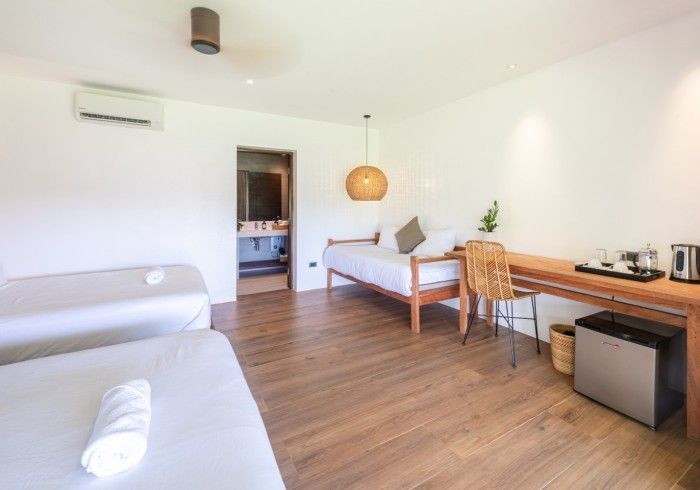 A hotel room with two beds , a desk , and a refrigerator.