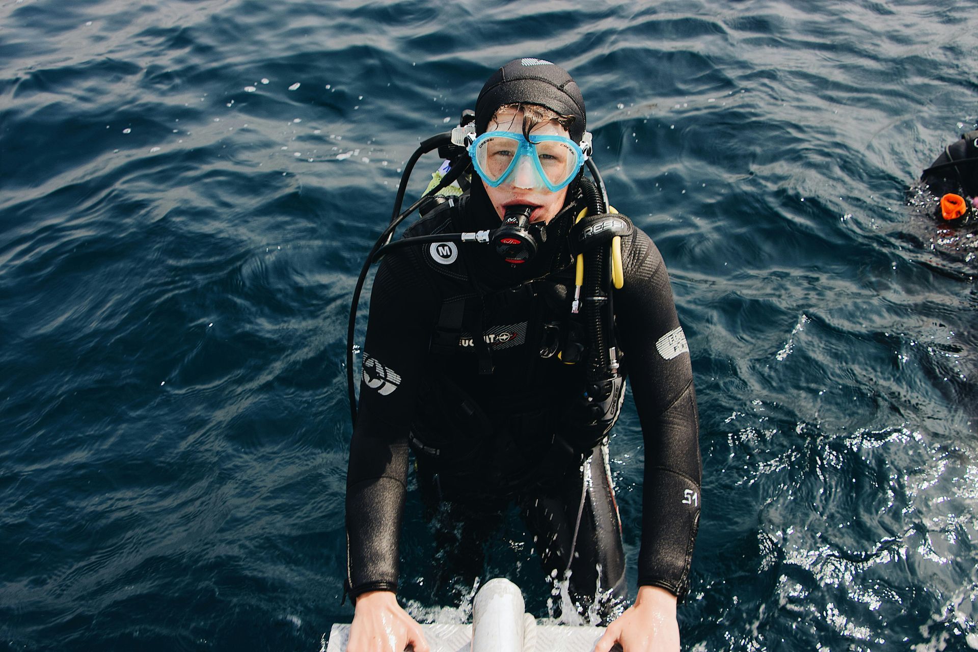A scuba diver is standing on a boat in the ocean.