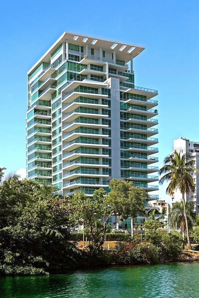 A tall building with a lot of windows is next to a body of water.