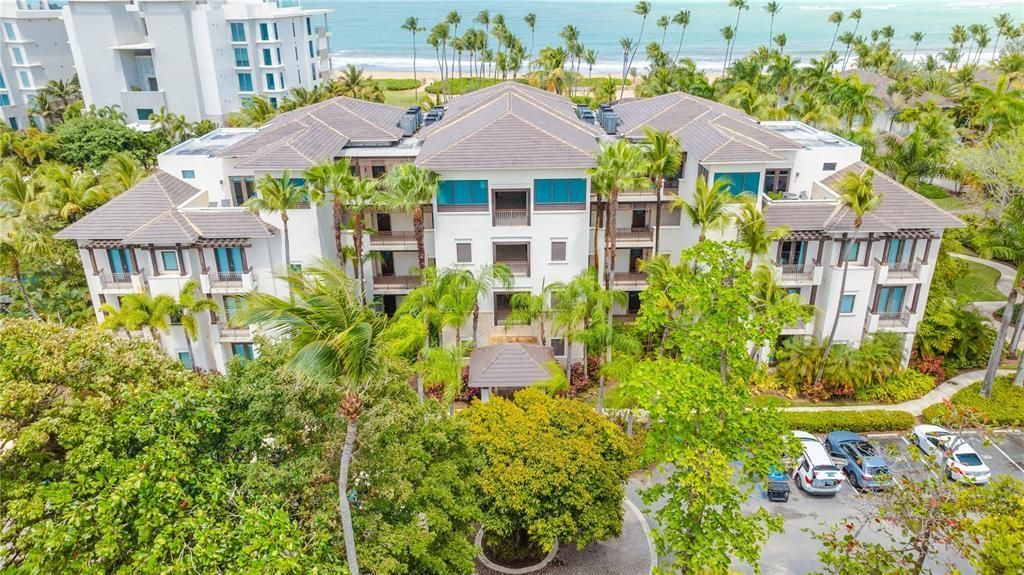 An aerial view of a large building surrounded by trees and palm trees.