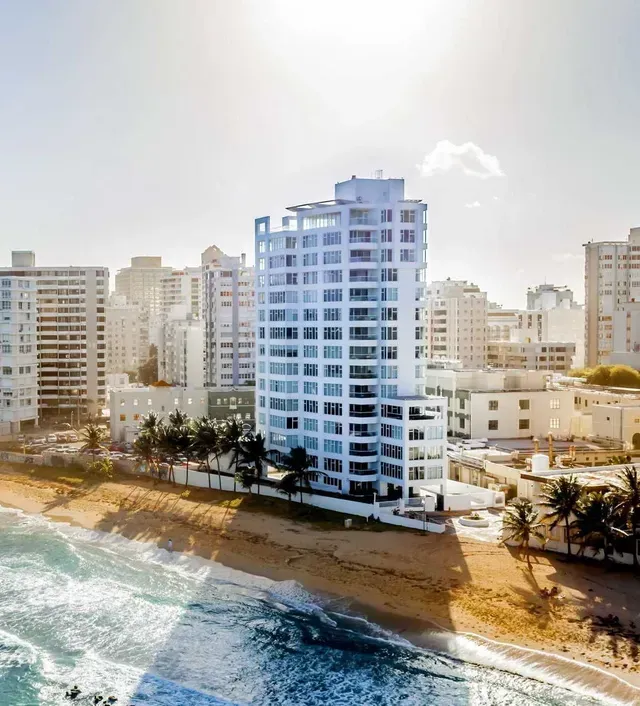 An aerial view of a city and a beach with a tall building in the foreground.