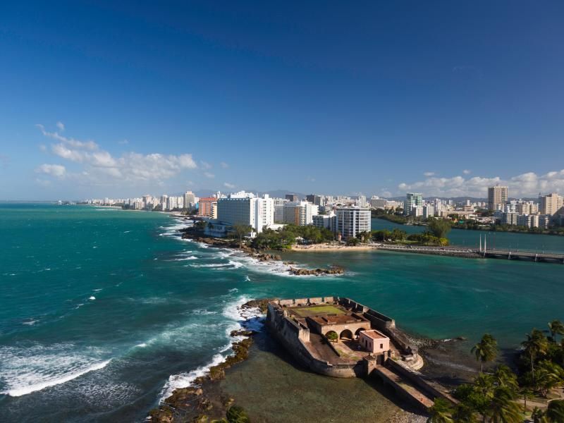 An aerial view of a small island in the middle of the ocean with a city in the background.