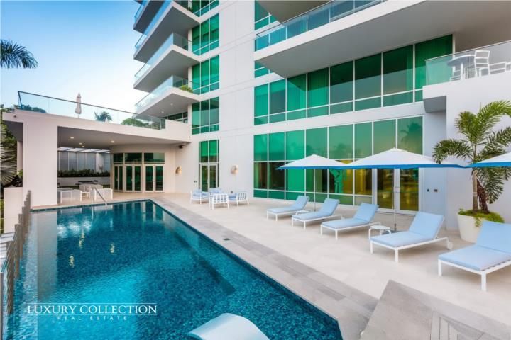 A large swimming pool with a view of a city and the ocean.