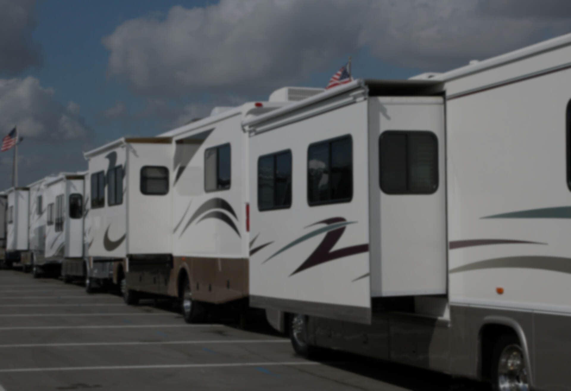A row of recreational vehicles are parked in a parking lot