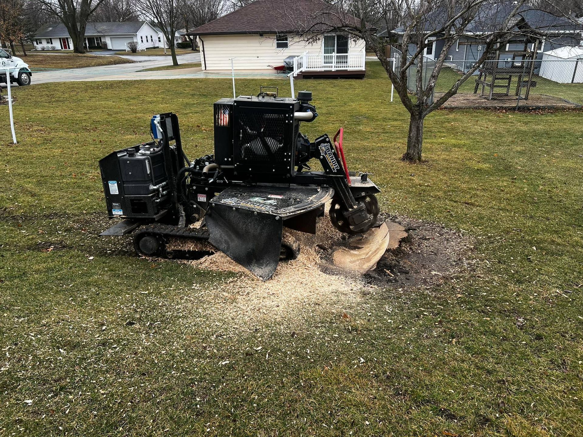 A stump grinder is cutting a tree stump in a yard.