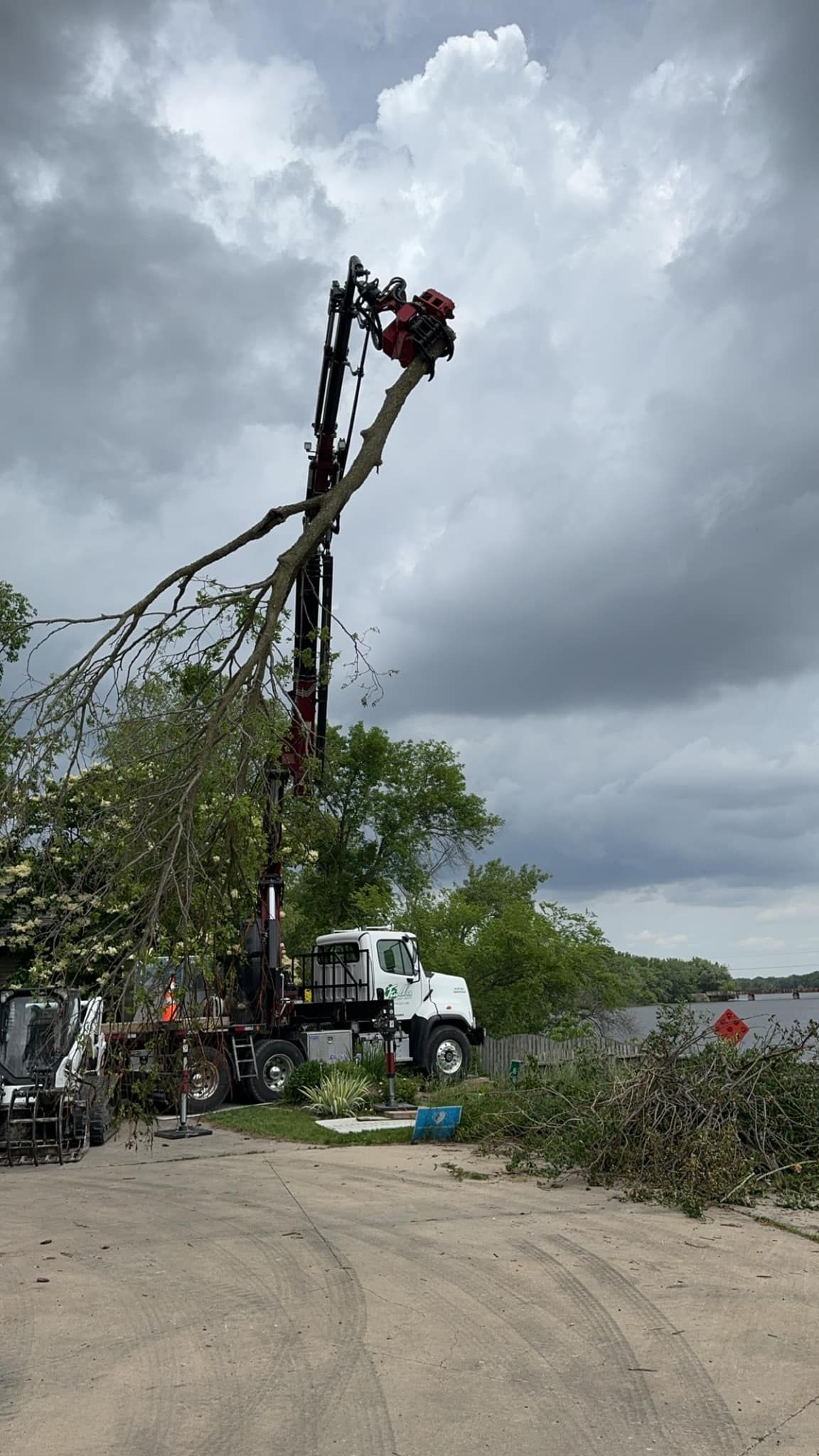 A man wearing a hard hat is carrying a chainsaw on his shoulder.