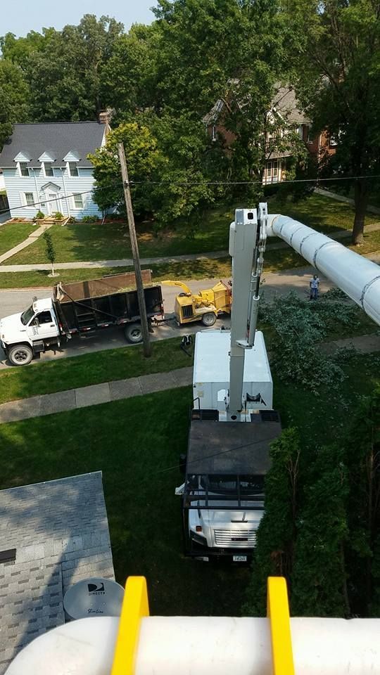 A white truck with a crane on top of it is parked in front of a house.