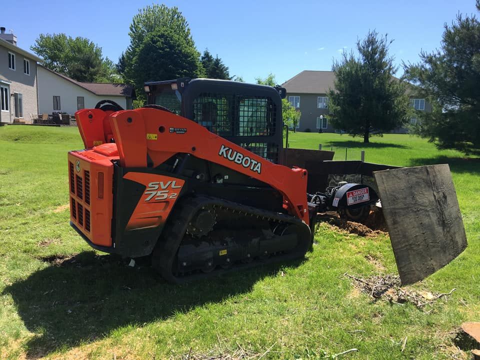 A kubota skid steer is parked in a grassy yard.