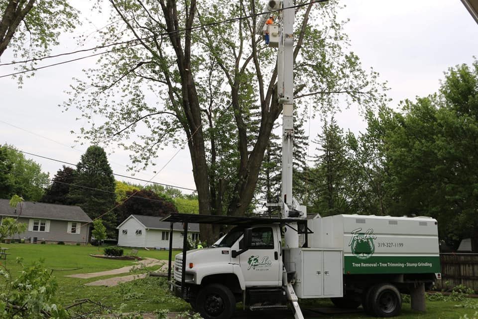 A tree trimming truck is parked in front of a house