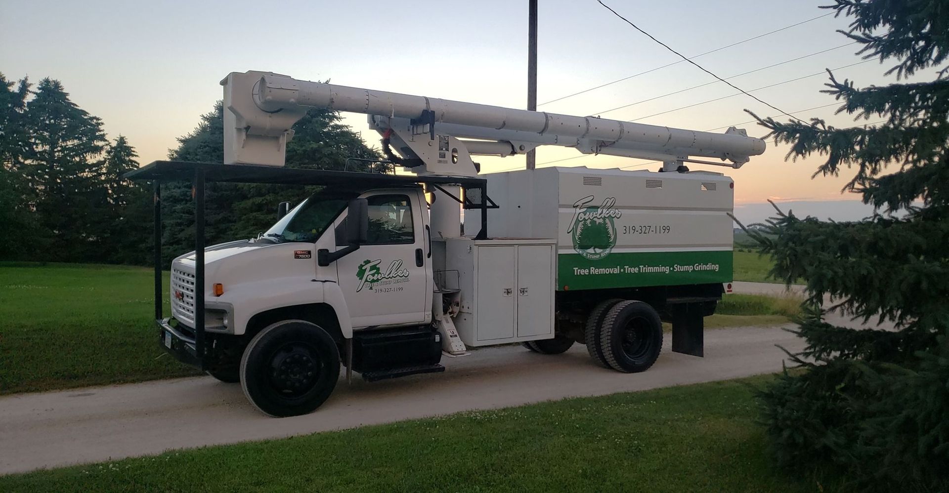 A white and green utility truck is parked on the side of a road.