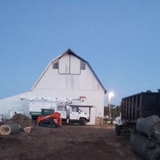 A white barn with a tractor parked in front of it.