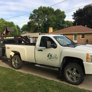A white tow truck is parked in front of a house.