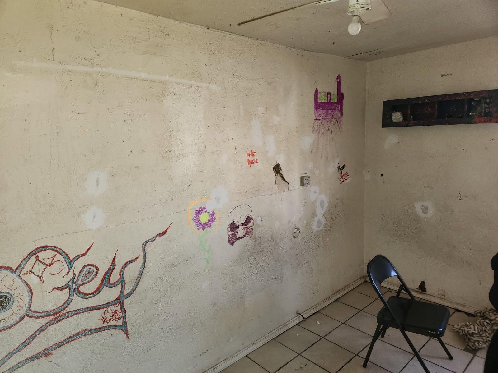 A room with a chair and a wall with graffiti on it.