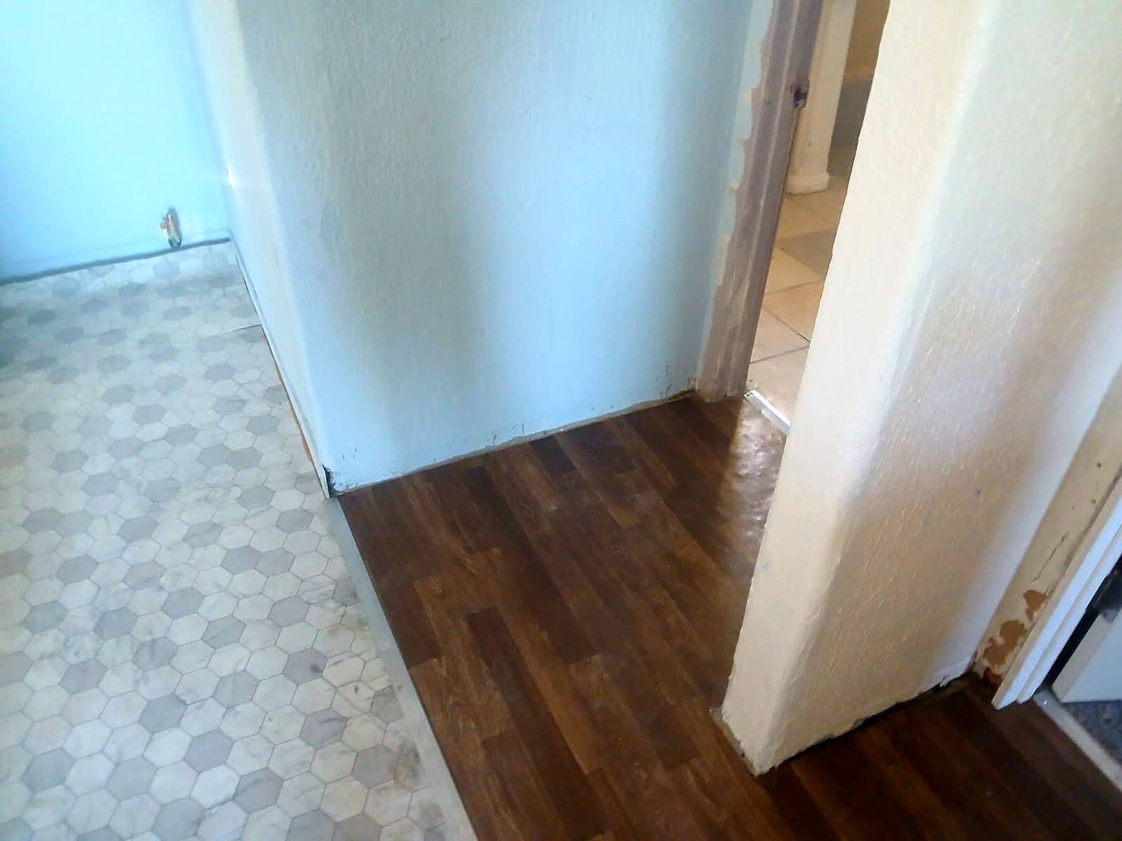 A hallway with a wooden floor and a white tile floor