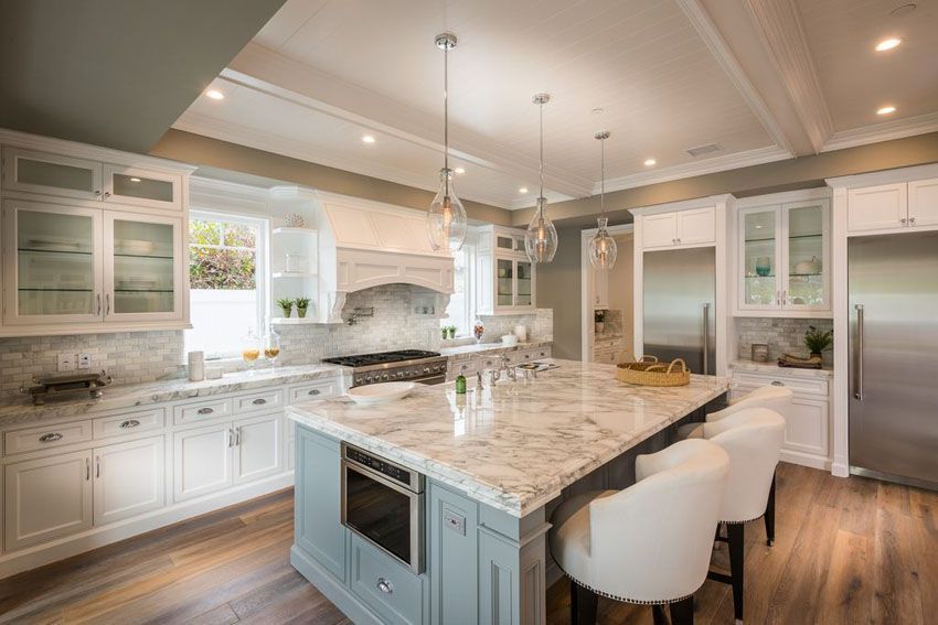 A kitchen with white cabinets , granite counter tops , stainless steel appliances and a large island.